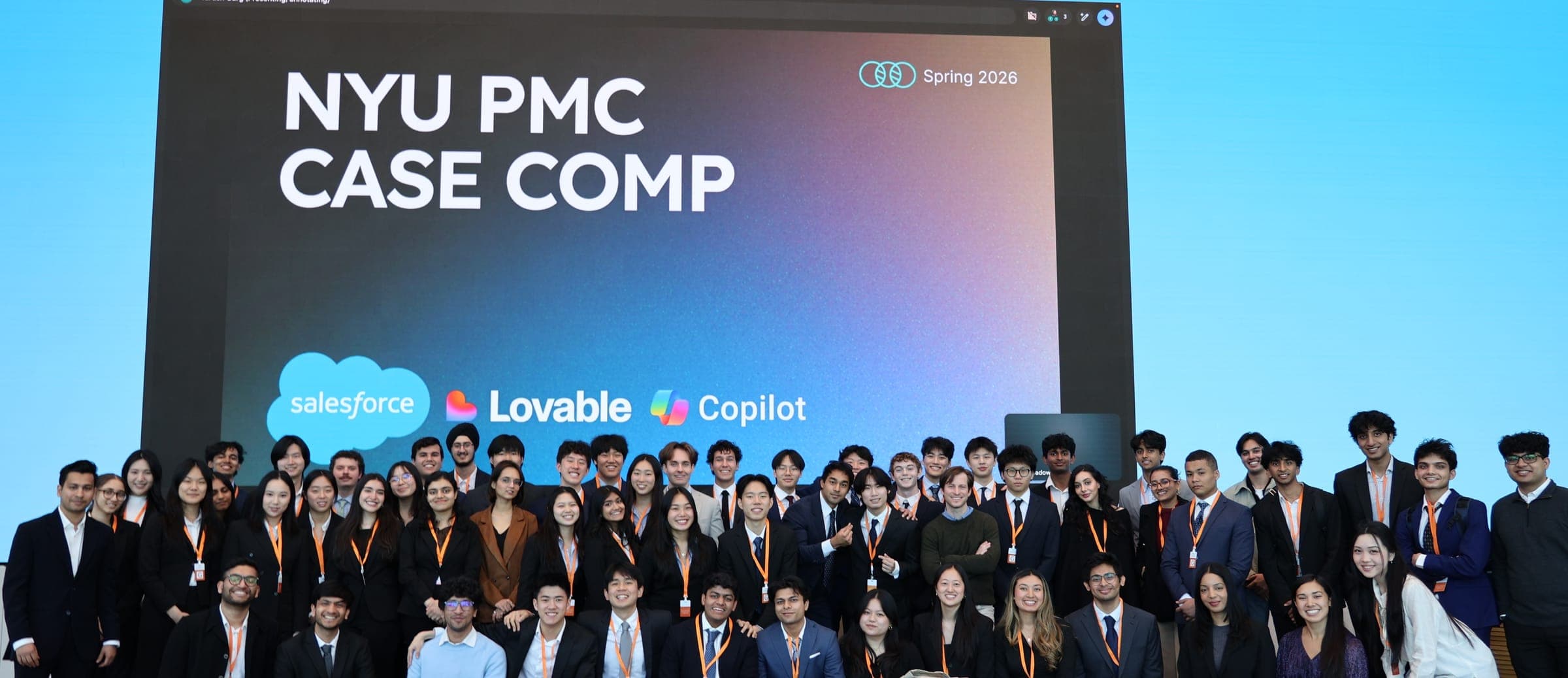 A large group of students in suits and orange lanyards in front of a screen reading NYU PMC Case Comp, Spring 2026, with Salesforce, Lovable and Copilot logos.